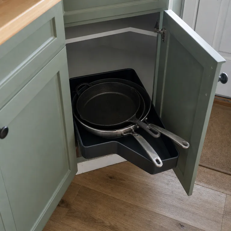 A low-sided tray of frying pans pulled from a diagonal corner cabinet.