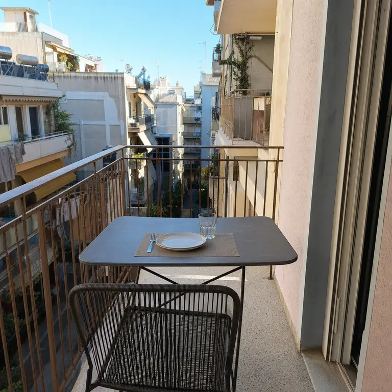 A narrow table and one chair make a solo outdoor dining spot on a balcony.