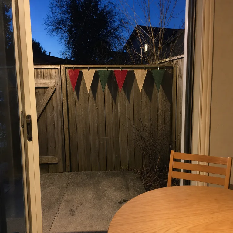 Reusable red, cream, and green fabric pennants clipped to a fixed fence panel beside a clear gate.