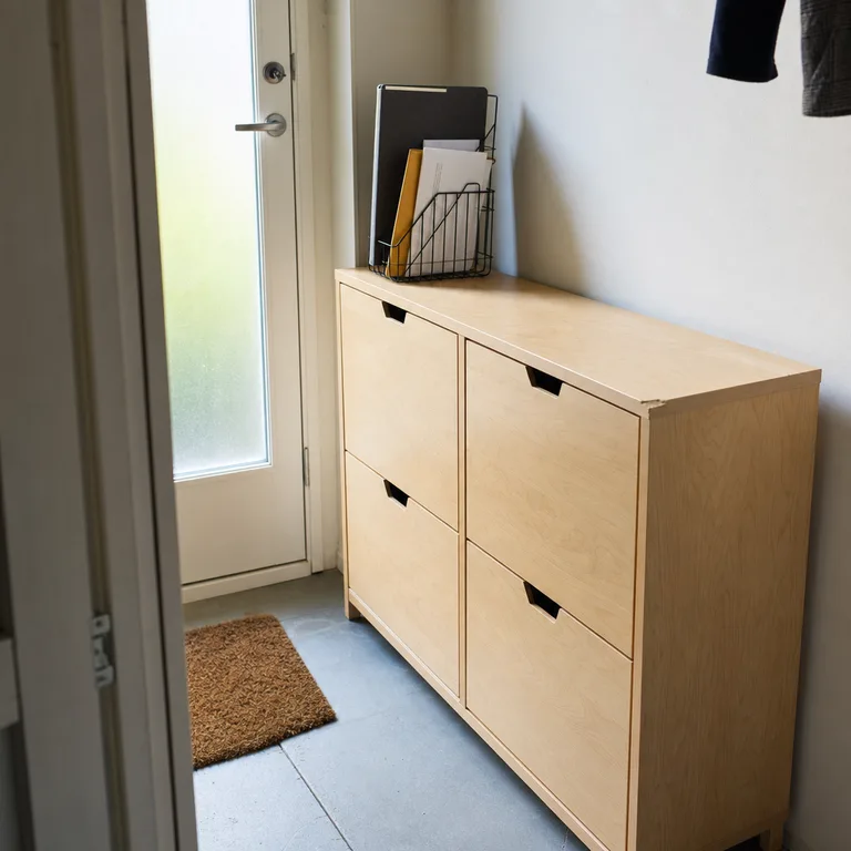 A wire file holder on a shoe cabinet keeps outgoing papers near the front door.