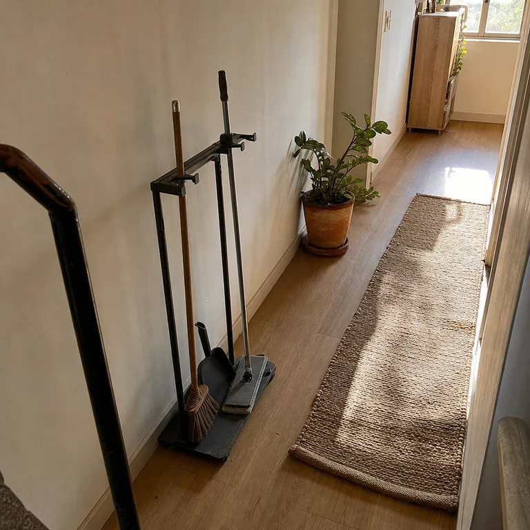 A narrow freestanding tool stand holds cleaning tools in a rental hallway.
