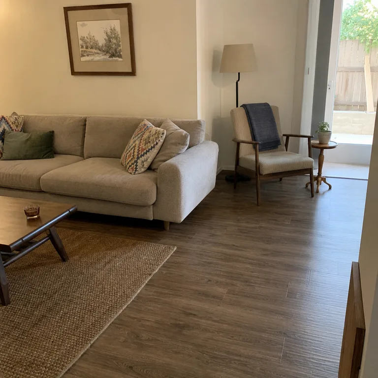 A narrow reading chair and small table placed behind the end of a sofa.