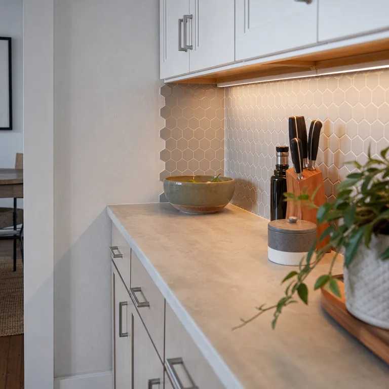 Soft gray small hexagon decals cover a contained backsplash section in a rental kitchen.