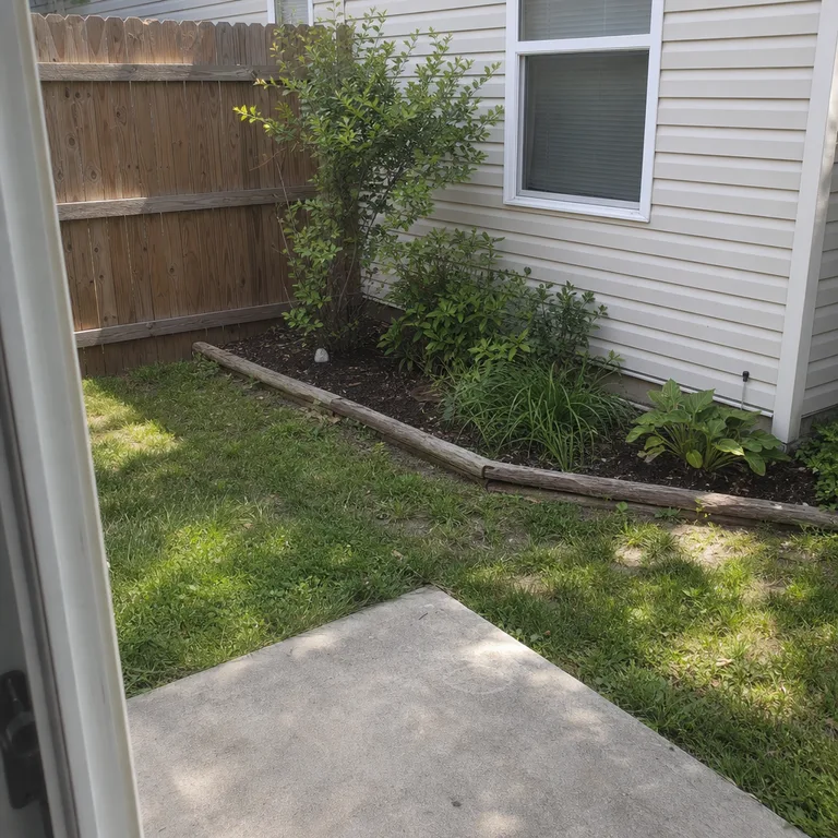 A small edged planting patch in a sunny backyard corner beside a patio.