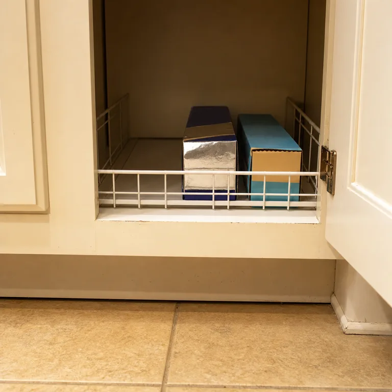 Boxed foil and parchment held in a front lane on a base cabinet shelf.
