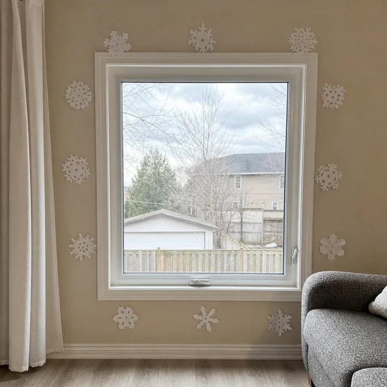 Paper snowflakes attached around the edges of a living room window while the center and latch stay open.