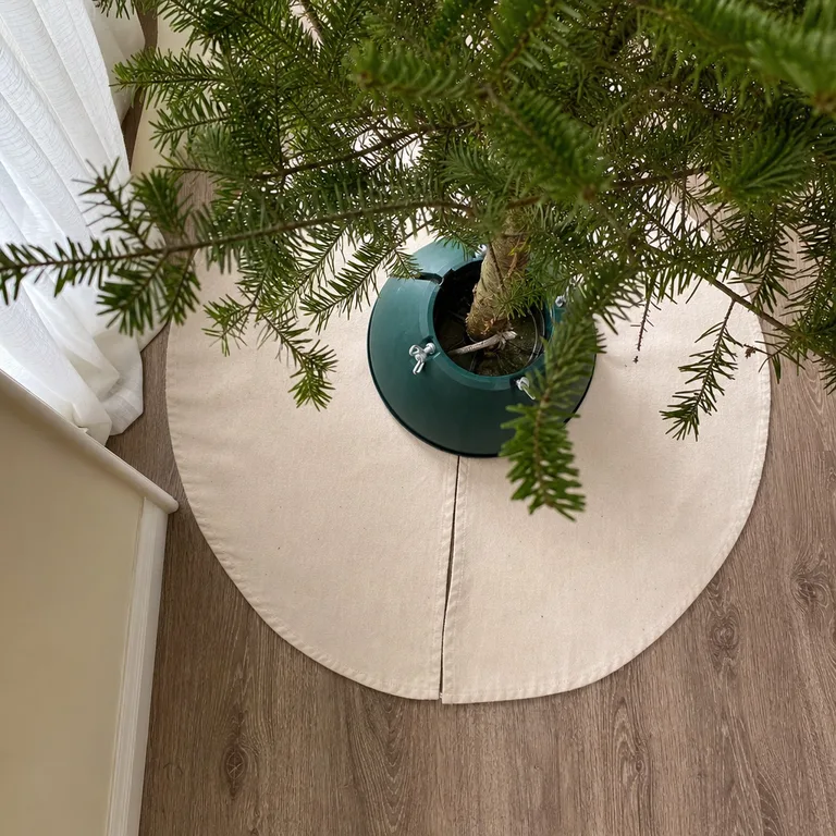 An overhead view of a plain canvas tree skirt with a center split around a green stand.
