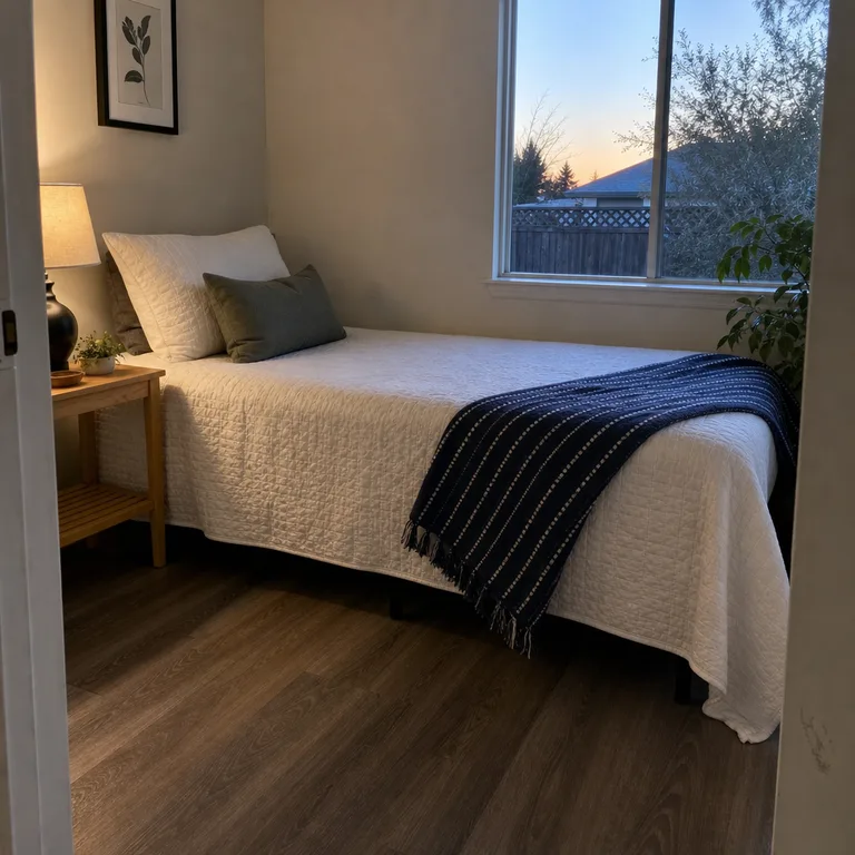 A navy striped throw laid diagonally across a white quilt on a twin bed.