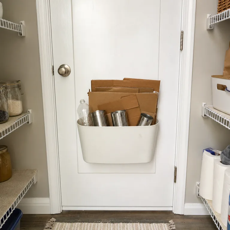 Shallow recycling bin hung over the inside of a pantry door.