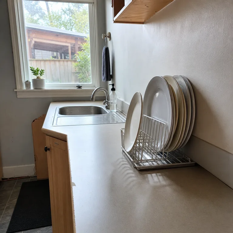 Slim wire plate rack and drip tray fitted along the narrow side of a small kitchen sink.