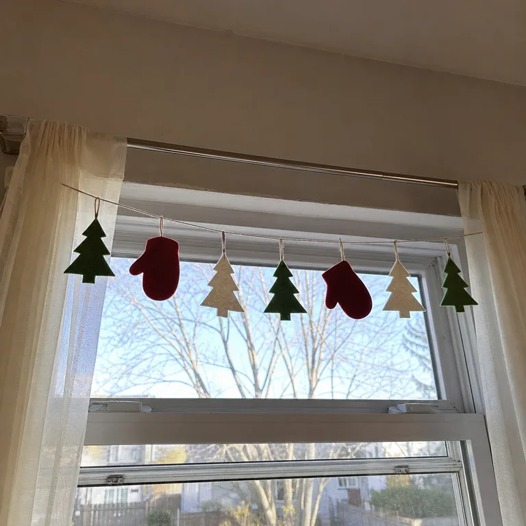 Flat felt ornaments strung across the upper third of a window, leaving the lower glass usable.