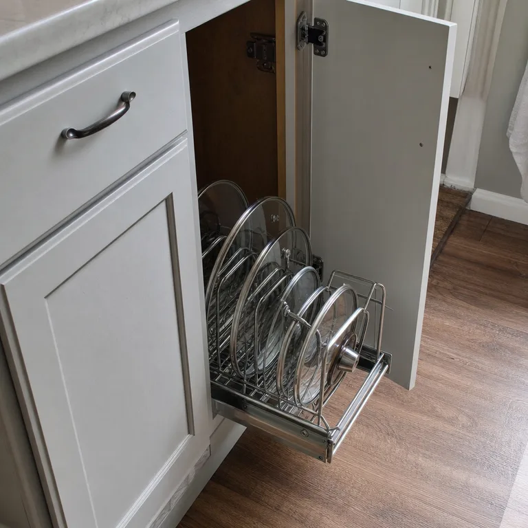 Pull-out cabinet organizer bringing pot lids forward in a lower cabinet.