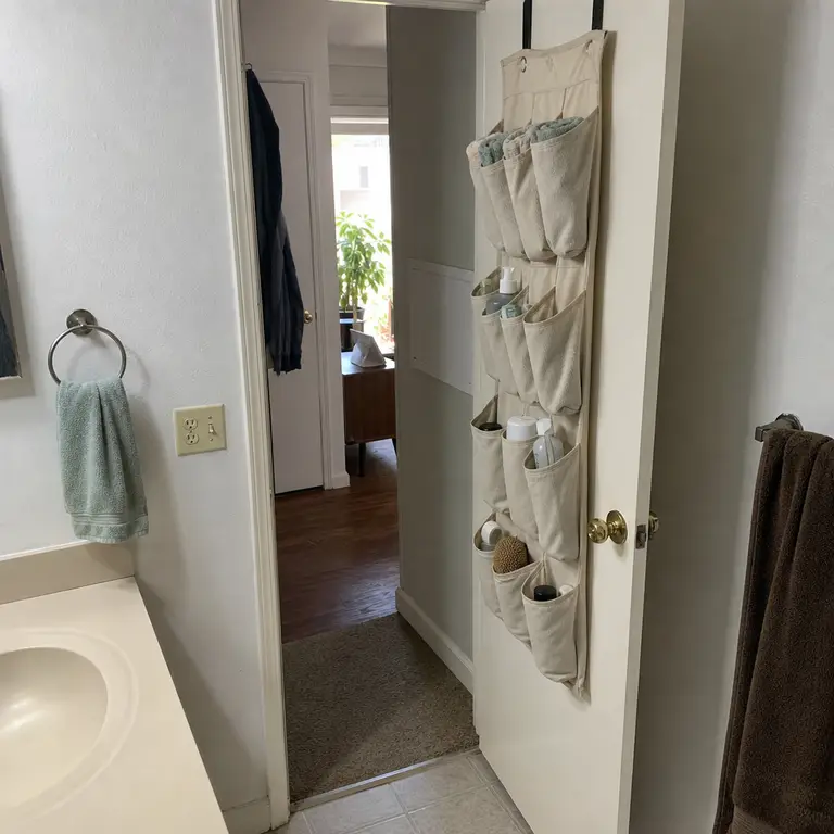 Over-the-door pocket organizer storing washcloths and small bathroom supplies.