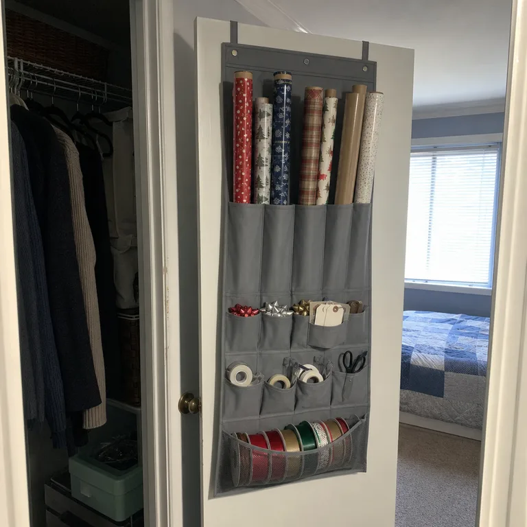 An over-door organizer inside a bedroom closet holding gift-wrap rolls, tags, tape, and scissors.