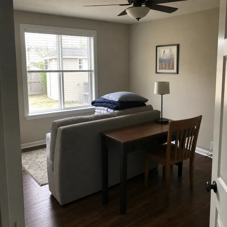 Narrow desk placed behind a compact sleeper sofa in a small room.