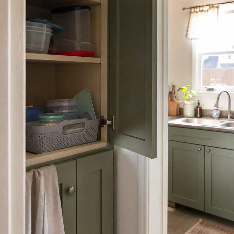 A handled cabinet basket holding small lunch containers and lids together.