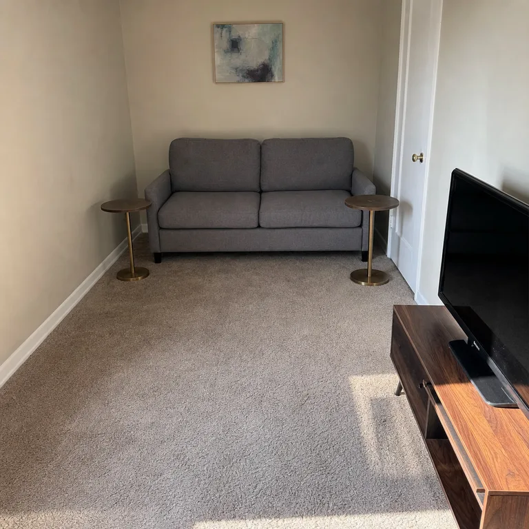 Two small round tables at either end of a gray sofa keep the center floor open.