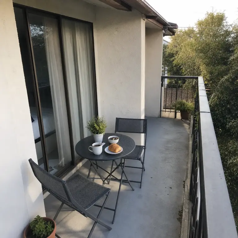 A compact bistro table and folding chairs form a breakfast corner on a small balcony.