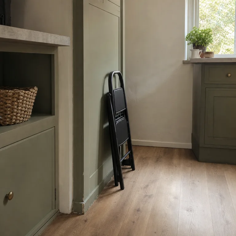 A folded black step stool stored along the side of a narrow kitchen pantry.
