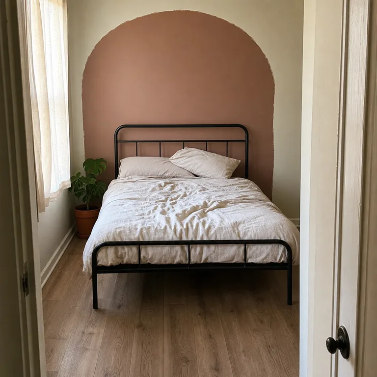 Basic metal bed frame centered against a hand-painted clay arch on a bedroom wall.