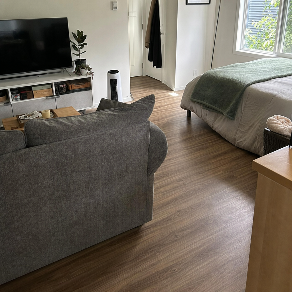 A sofa placed with its back toward the bed to define a studio living area.