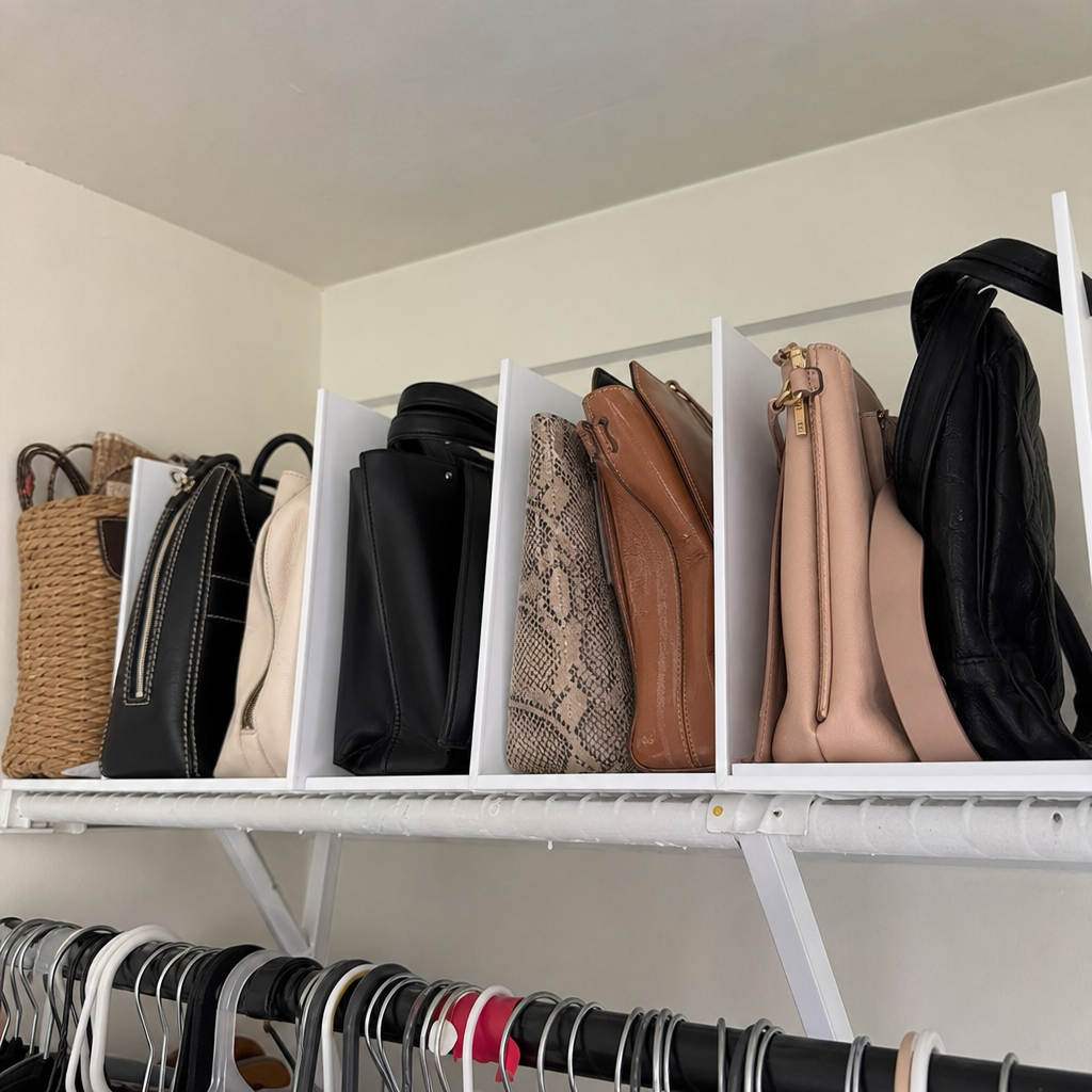 Handbags stand upright in divided sections on a closet shelf.