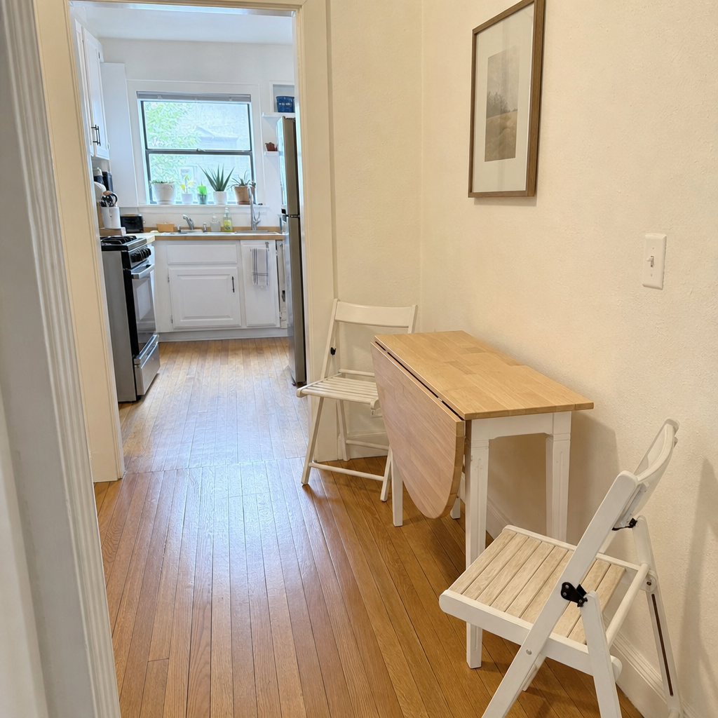 Wall-mounted drop-leaf dining table with an open leaf and folding chairs in a small kitchen.