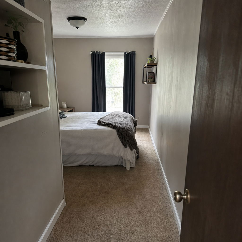 A queen bed turned across the end of a narrow bedroom, leaving a side walkway.